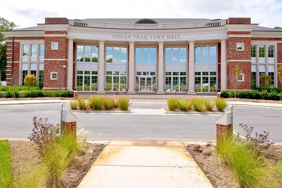 Indian Trail Town Hall, a two-story brick building with white columns and tall windows, under a bright summer sky
